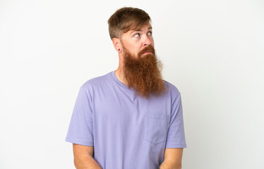 Fototapeta premium Young reddish caucasian man isolated on white background making doubts gesture looking side