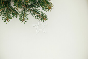 Stylish christmas ornaments on fir branches against white background. Modern glass baubles on xmas tree branches,  scandinavian decoration in festive room, space for text