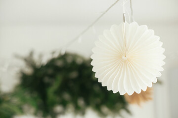 Stylish paper christmas stars hanging on background of festive decorated boho room. Handmade paper...