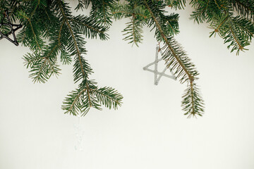 Fototapeta na wymiar Stylish christmas ornaments on fir branches against white background. Modern glass baubles on xmas tree branches, scandinavian decoration in festive room, space for text