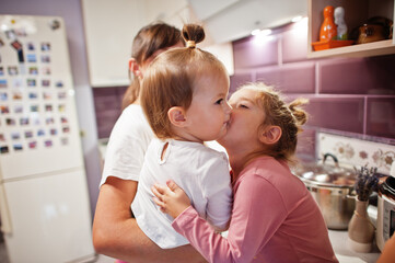 Mother with kids cooking at kitchen, happy children's moments. Two sister kissing.