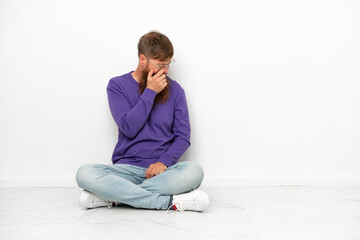 Young caucasian reddish man sitting on the floor isolated on white background laughing