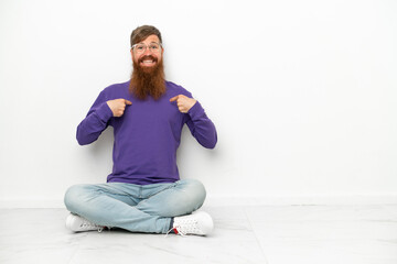 Young caucasian reddish man sitting on the floor isolated on white background with surprise facial expression