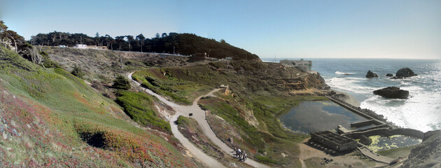 Panoramic of Waves roll towards shore of Ocean Beach with Cliff House and the ruins of the Sutro Bath House