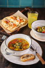 Set meal of three courses, soup, salad, Roman pizza halves and lemonade in glass