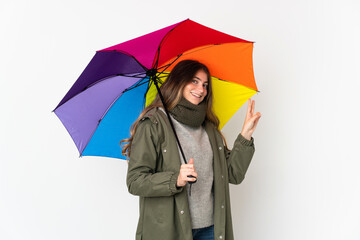 Young caucasian woman holding an umbrella isolated on white background smiling and showing victory sign