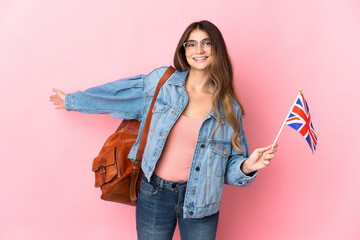 Young woman holding an United Kingdom flag isolated on pink background extending hands to the side for inviting to come