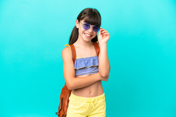 Little caucasian kid going to the beach isolated on blue background with glasses and happy