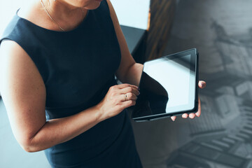 Businesswoman working on tablet in office. Mature woman using touch pad computer standing by window...