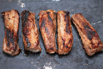 appetizing fried pork ribs, meat on the bone on a dark background
