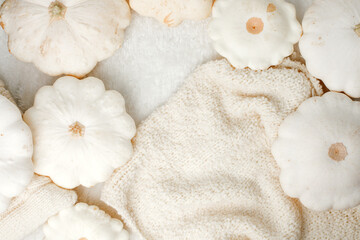 Autumn composition. Feminine desk table with knitted scarf and white squash pumpkin on white background. Flat lay, top view. Nordic, hygge, cozy home concept, monochrome, copy space