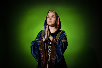 A fortune teller in a traditional dress with a rosary in her hands prays, a portrait on a dark background, hard light