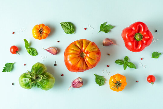 Food composition. Tomatoes, basil, garlic and pepper on pastel blue background. Flat lay. Top view