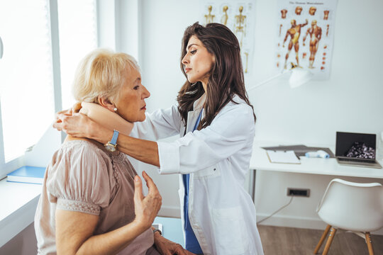 Doctor applying cervical collar on neck of senior woman in clinic. Female doctor putting neck orthopaedic collar on adult injured woman. Woman in pain at the doctor for a neck injury