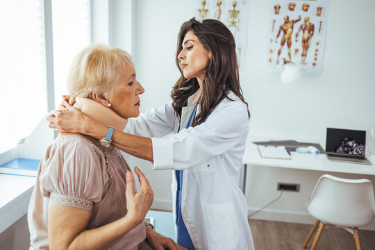 Young woman with injury of neck visiting doctor in clinic. Doctor examining a patient at desk in medical office. Doctor talking to a senior patient with cervical collar at the hospital