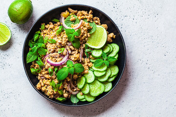 Thai chicken salad larb gai with onion, cucumber and mint. Asian food concept.