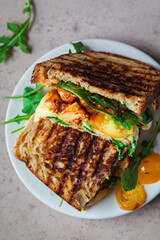 Grilled sandwich with vegetables and mozzarella on wooden board.
