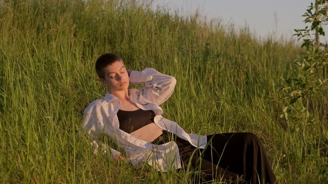 Woman dreaming during sunset on summer meadow. Woman relaxing outdoors. 4K, UHD