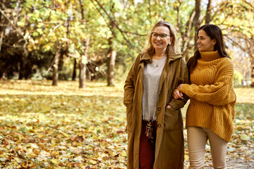 Fototapeta premium Senior woman with her adult daughter walking at the par during the autumn