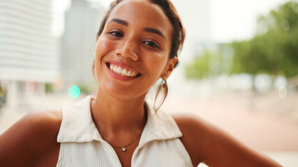 Close-up of the face of beautiful tanned woman with dark hair and expressive brown eyes looks at the camera with smile