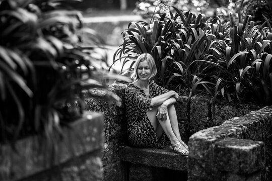 A woman on a stone bench in old parkl. Black and white photo.