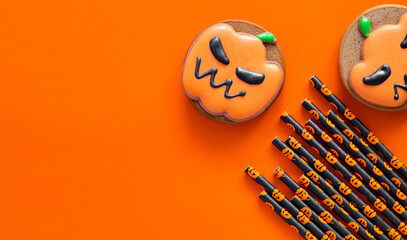 Orange pumpkin shaped gingerbread cookies and cocktail tubes for Halloween party on an orange...
