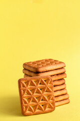 Obraz na płótnie Canvas Stack of square golden biscuits on a yellow background. Copy space.