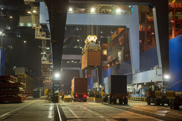 operation of container terminal at night. Unloading container ship at night. Mooring cranes unload...