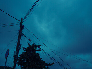 Storm clouds with a little sunlight peaking through over a light post and trees