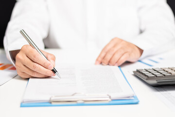 professional businessman hand holding pen writing and sign paperwork or document finance indoor at office, man manager person handwriting paper on clipboard and signature agreement approval business