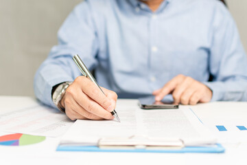 professional businessman hand holding pen writing and sign paperwork or document finance indoor at office, man manager person handwriting paper on clipboard and signature agreement approval business