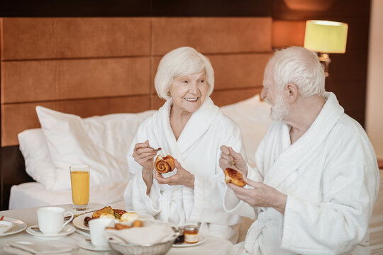 A senior happy couple enjoying breakfast while staying in bed - Powered by Adobe