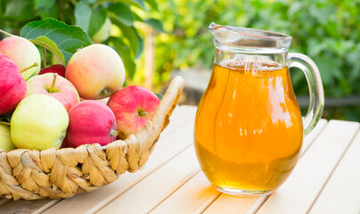 Glass decanter with apple juice on a table in the garden