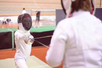 two fencers in white uniforms  are training to participate in a duel