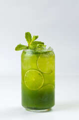 green cocktail with lime, syrup and soda with ice cubes