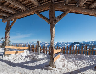 viewpoint at Hartkaiser mountain with wooden shelter and telescope, sunny winter landscape tirol
