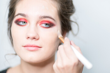Performing bright makeup close-up. Red tones.