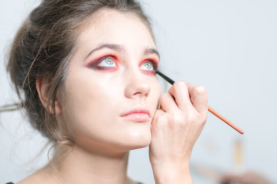 Performing bright red makeup close-up.  Expressive look.