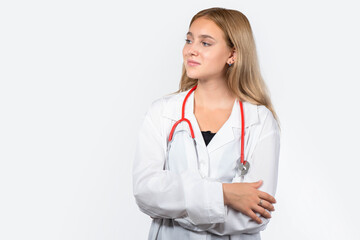 Young nurse. Blond woman in doctor uniform. Hospital worker in white coat. Girl nurse with stethoscope around her neck. Concept of career in hospital. Confident nurse stands with her arms crossed