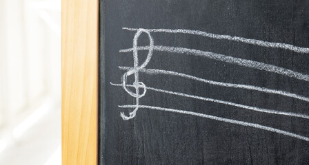 Fototapeta na wymiar Treble clef on a chalkboard drawn by a child, chalk drawing, object detail, closeup, front view, nobody. Music, violin clef musical symbols, notation and kids education abstract concept, no people