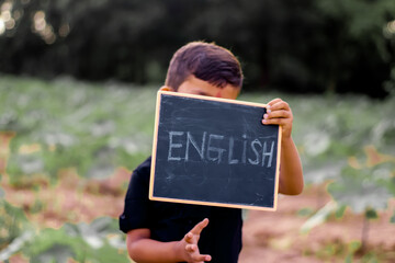 5 year old boy holding blackboard and learn English language in village,indian child english...