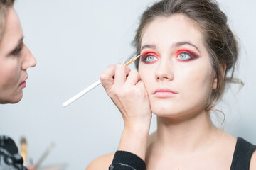 Obraz premium Makeup model. Makeup artist performs make-up in bright colors. Close-up.