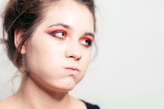 A girl with pouty cheeks, bright red eye makeup. Close-up.