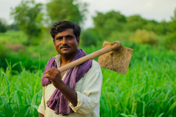 happy farmer is holding shovel in millet field, - obrazy, fototapety, plakaty