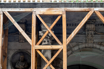 Old antique Corinthian Greek column capital top part and a wooden scaffolding closeup, nobody, no...