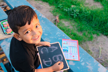 Indian 5 year child writing A B C D alphabet on chalkboard,abcd alphabet