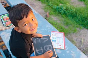English at alphabet on chalkboard with Asian child studying outdoor,