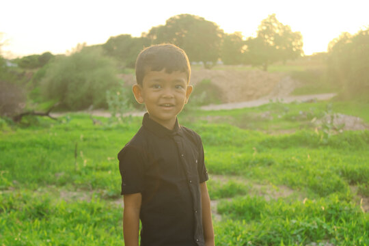 Indian 5 years old boy looking camera with smile,portrait of a five year old Indian boy wearing a shirt with sunlight,selective focus