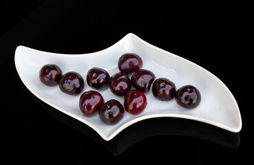 Cherries in a white ceramic bowl on a black background