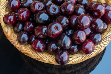 Close up of fresh ripe cherries , in a colorful wicker basket